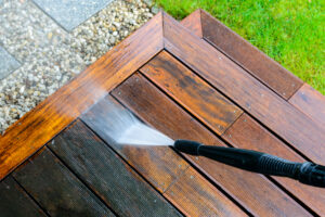 High Pressure Washer cleaning a wooden deck. Some boards are clean some are still dirty