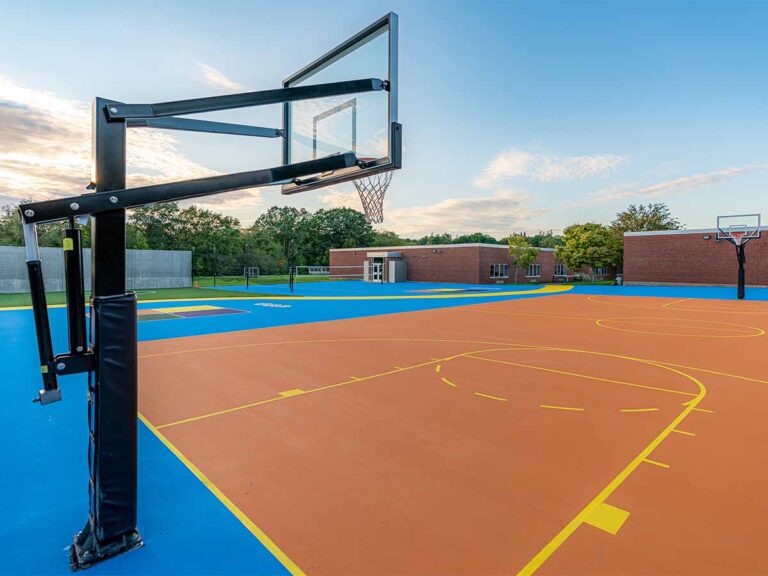Photo of clean High school Basket ball courts. One of the hoops is visible in the forfront of the photo