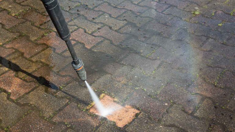 Photo displays a pressure washer cleaning a very dirty brick surface. Only 1 brick has been pressure cleaned