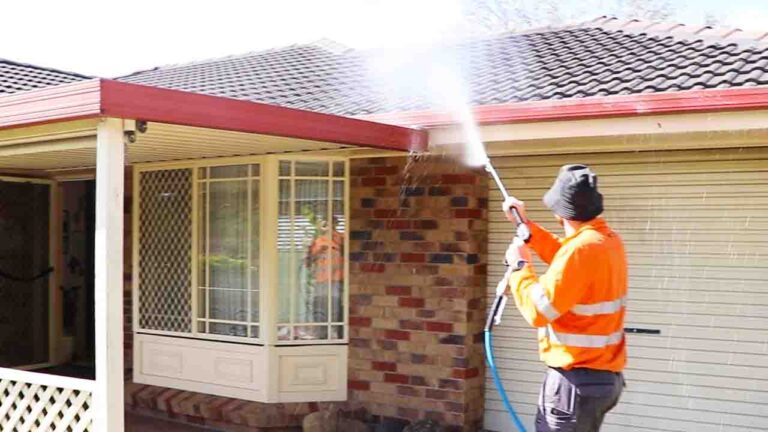 Team member of Pressure Washed South East QLD washing a single level brick house