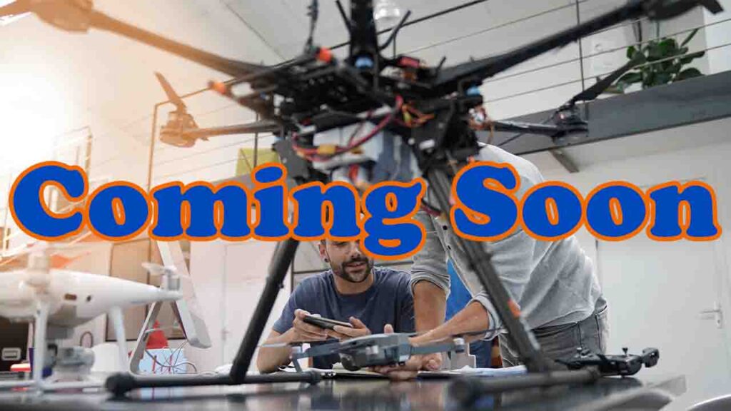 Large drone sitting on a work table with 2 people holding a remote control in the back ground.