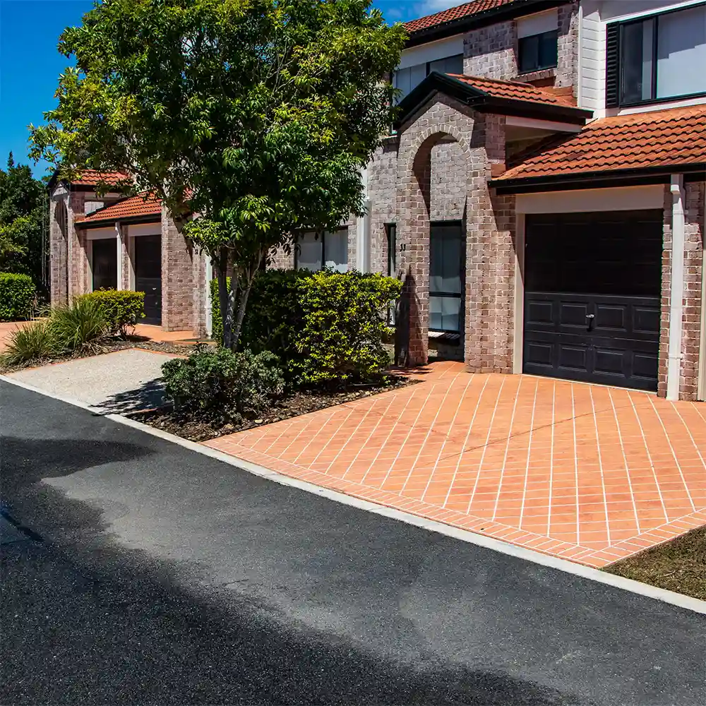 A body corporate managed Property aft it has been pressure cleaned my Pressure Washed South East QLD. The photo shows 4 units that are connected and are two story. The buildings are made from a light white colored brick and the driveways are paved orange. It's bright sunny day with blue sky. The buildings look very clean.