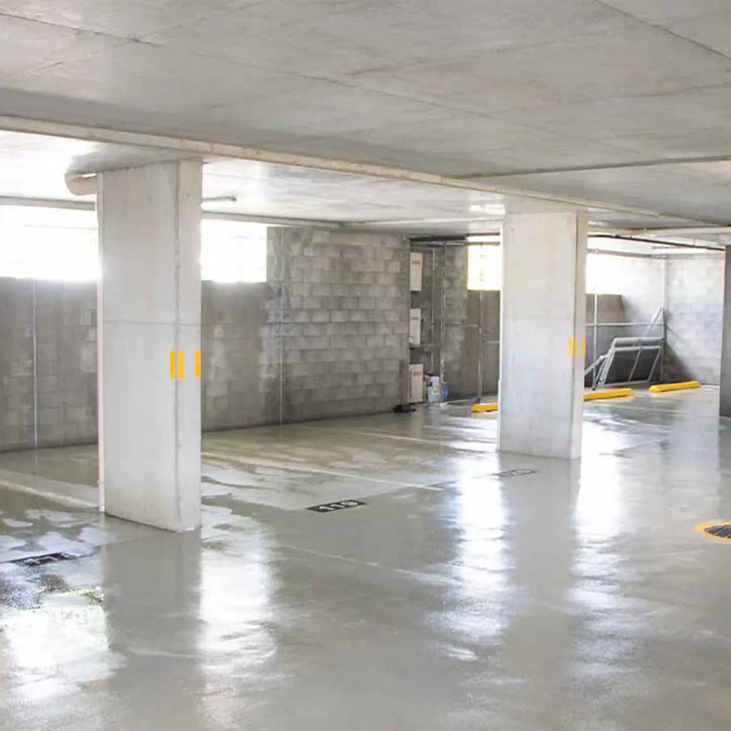 Photo of an underground car park that has just been pressure cleaned. The floor, walls and ceilings are made of grey concrete