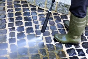 Man power washing a concrete and tile driveway